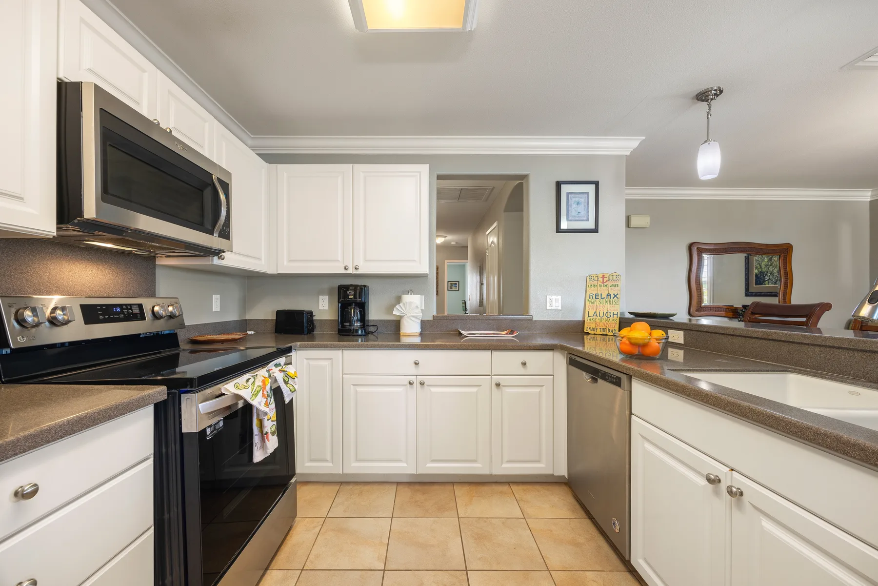 A bright kitchen with white cabinets, stainless steel appliances, and a central counter.