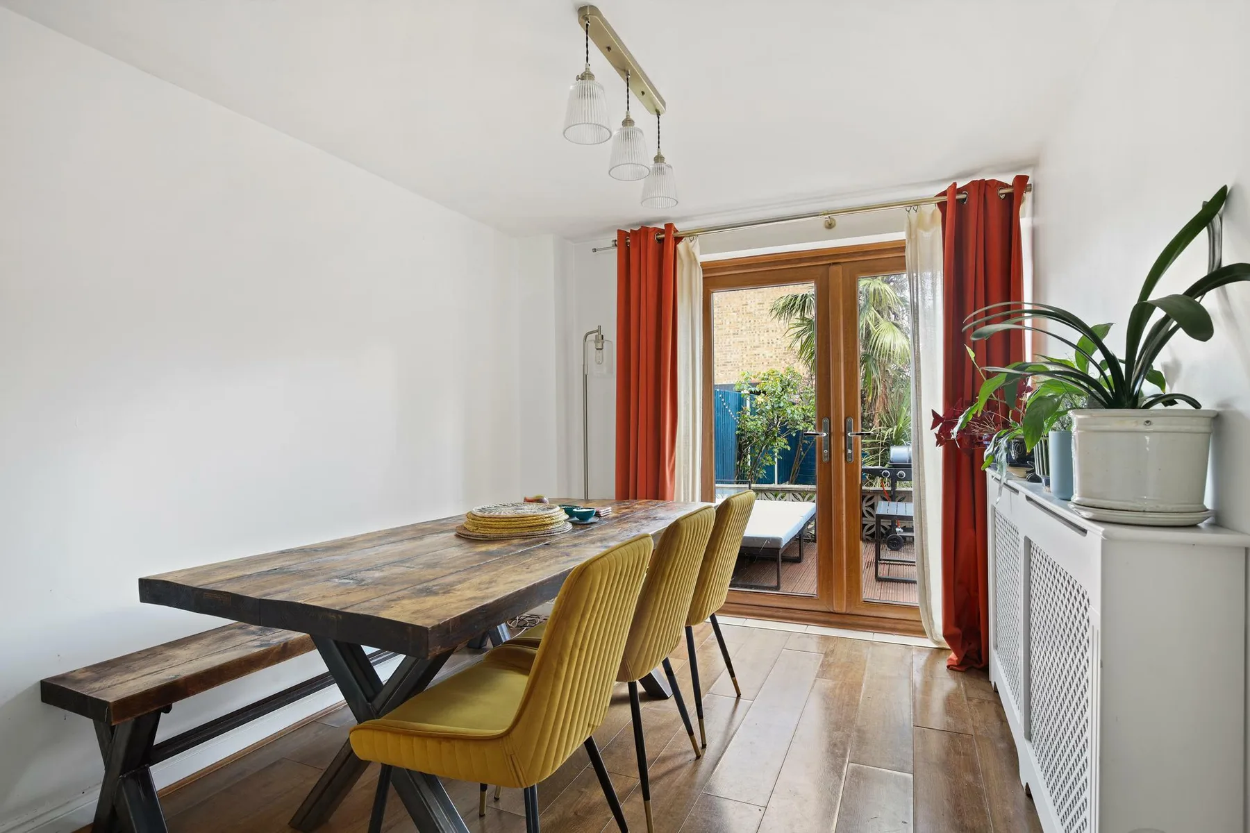 Comedor con una mesa de madera y asientos junto a puertas de cristal.