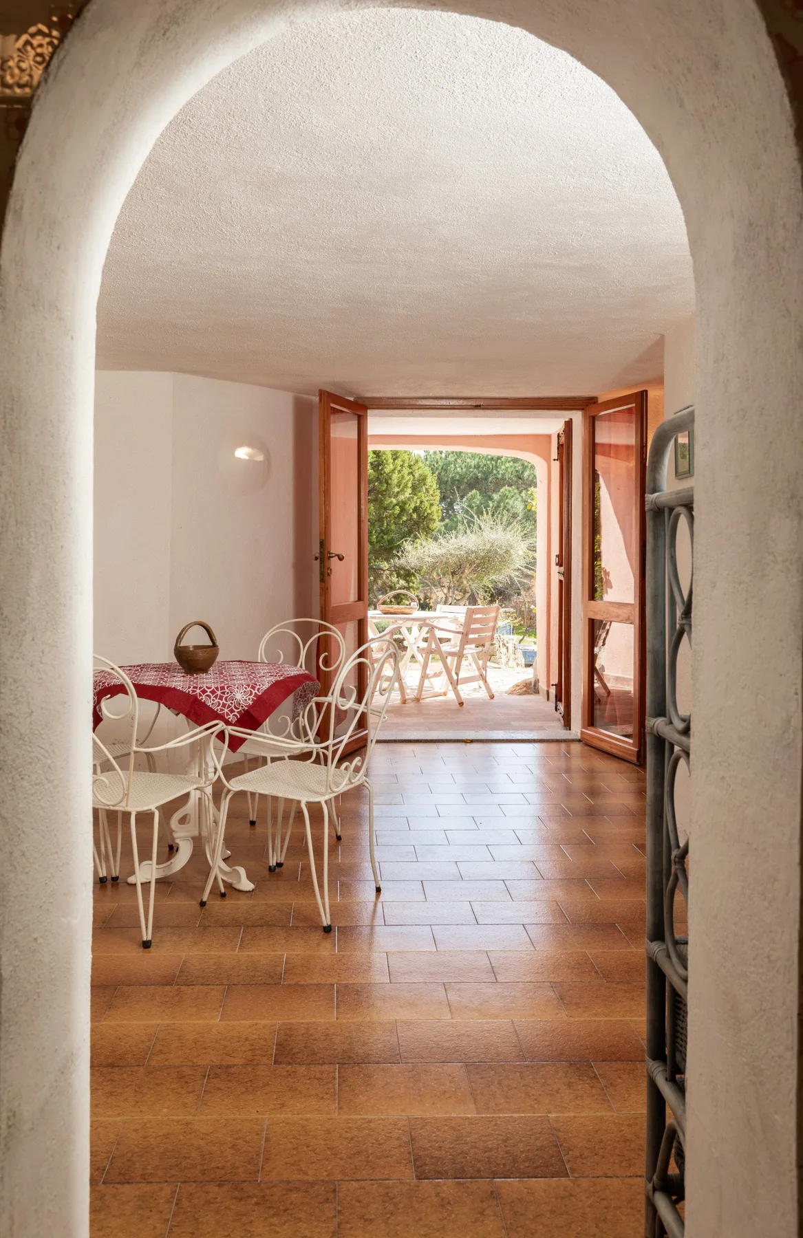 Un comedor se abre a un patio ajardinado a través de puertas de madera.