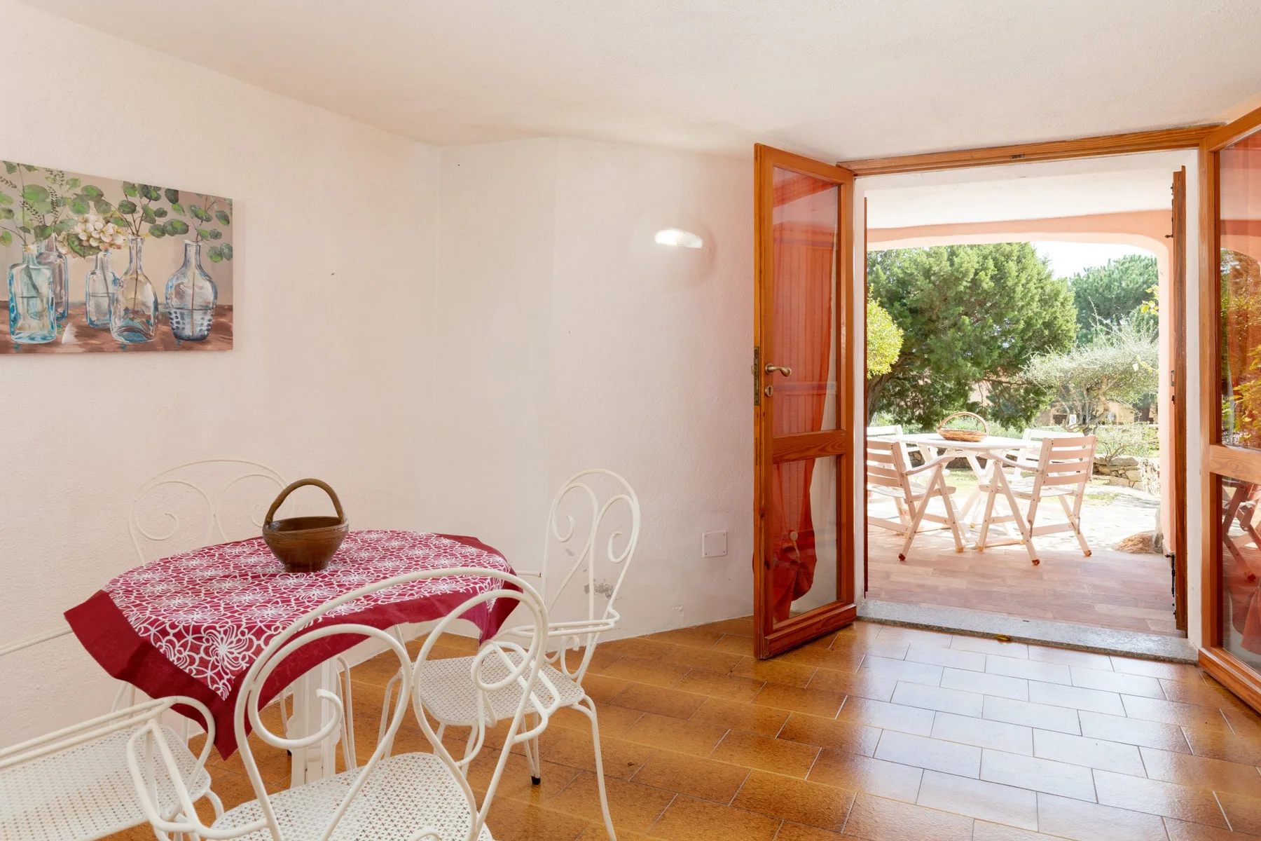 A dining area with a red-covered table and open doors leading to a patio.