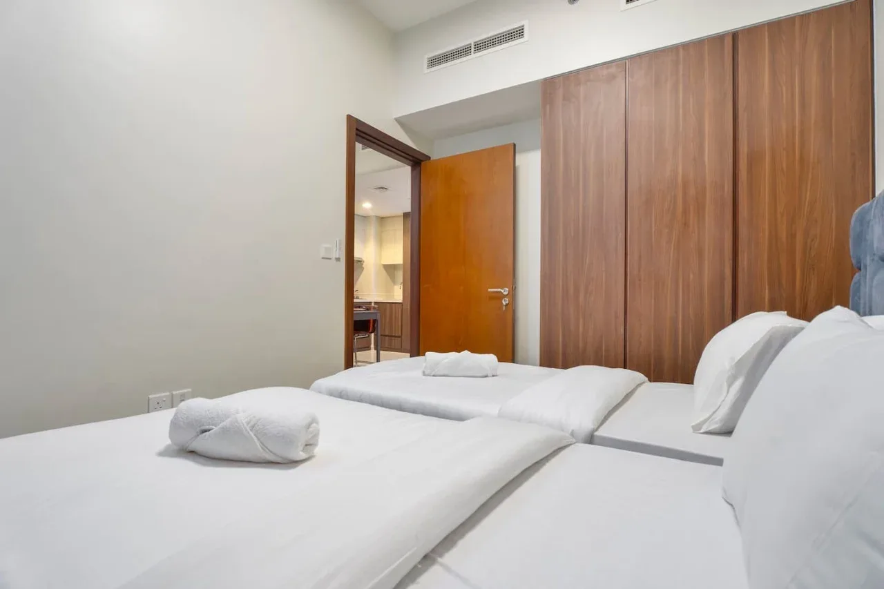 Un dormitorio con camas bien tendidas y un armario de madera.