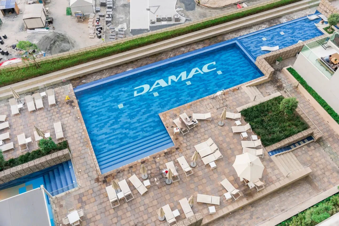 Vista aérea de una piscina con tumbonas en la terraza que la rodea.