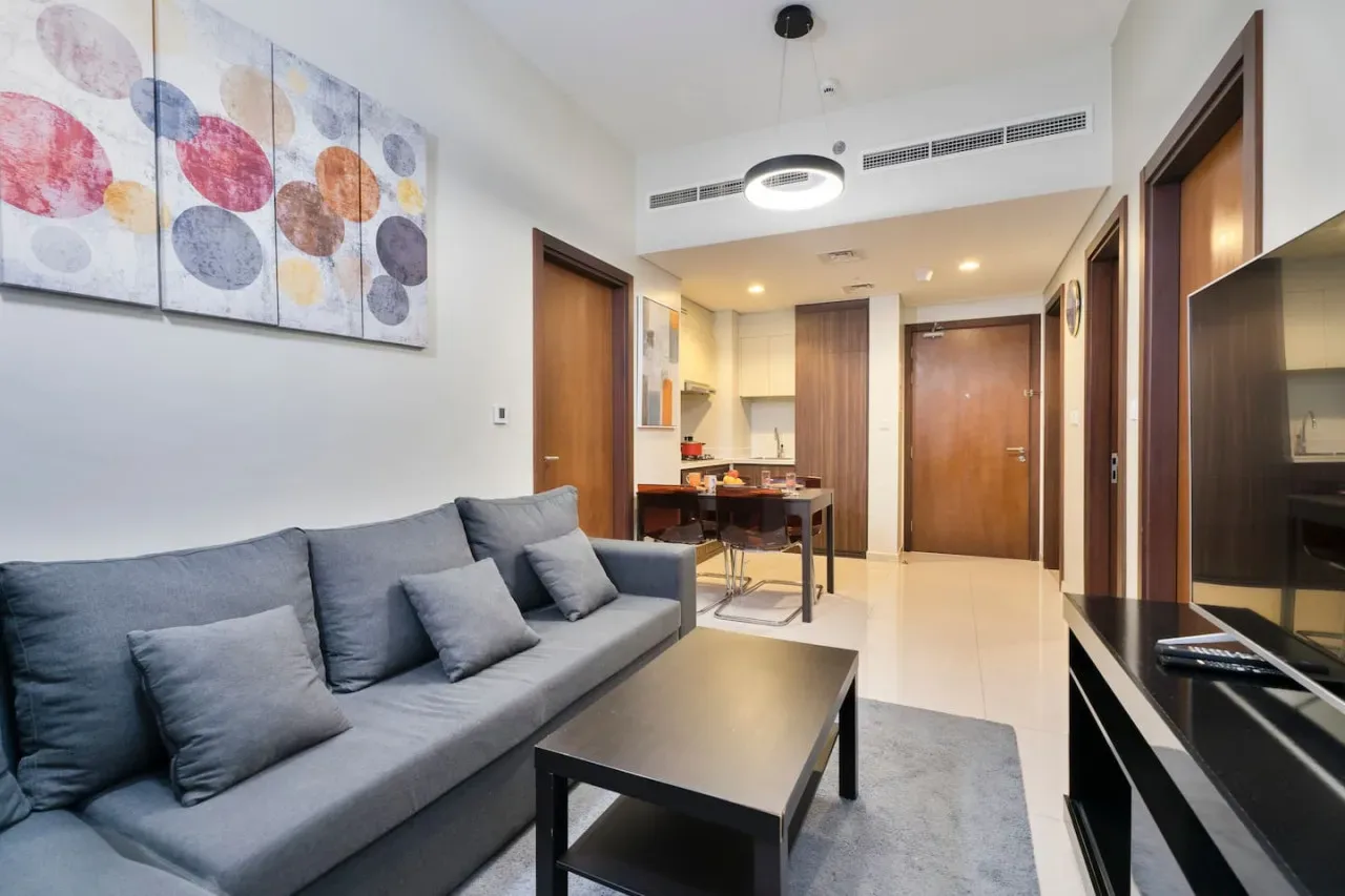 Una sala de estar moderna con asientos grises, una mesa de centro y un comedor.