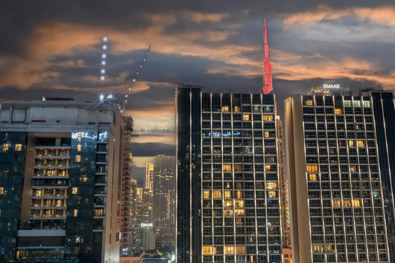 Los edificios altos de la ciudad brillan al atardecer bajo un cielo nublado.