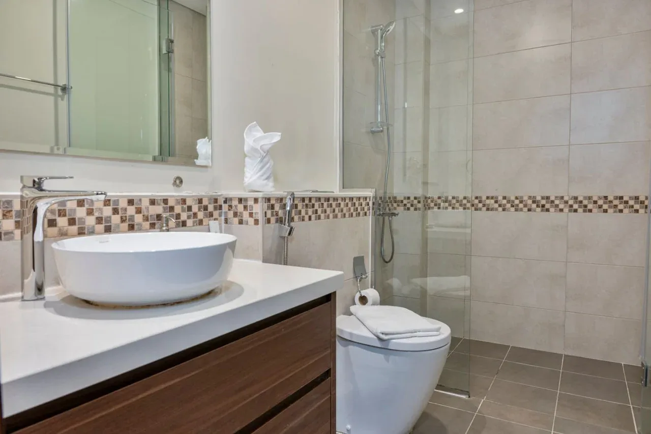 Un baño alicatado con lavabo, inodoro y ducha de vidrio.