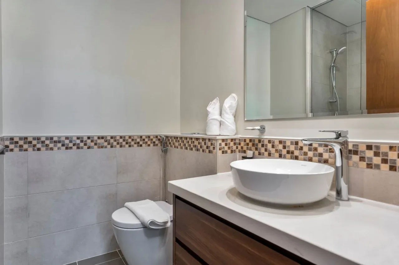 Un baño con lavabo, espejo y ducha.