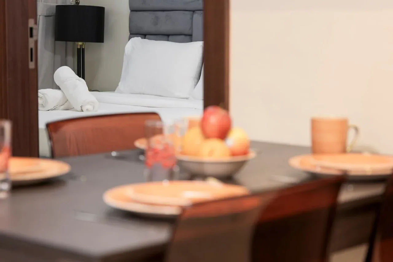 Una mesa con platos y fruta está frente a un dormitorio.