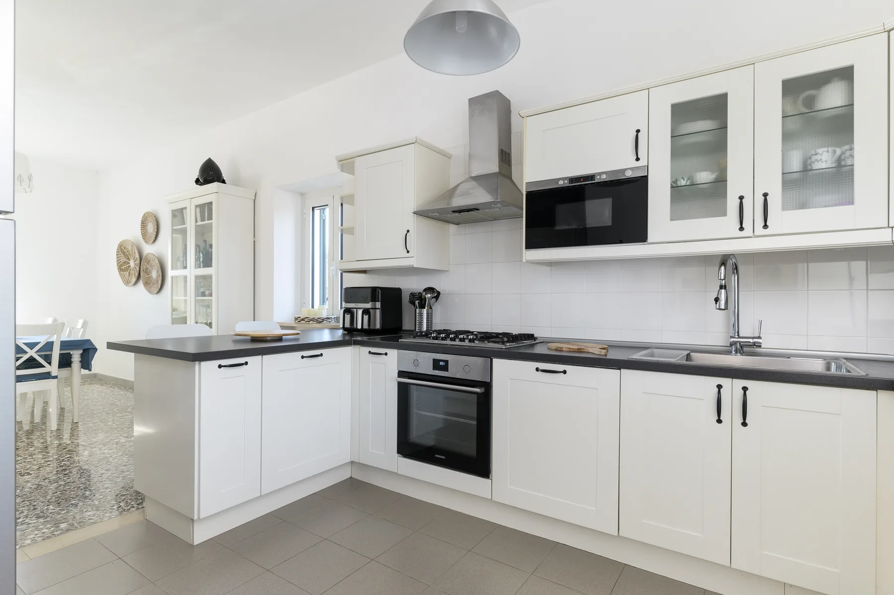 A bright kitchen with white cabinets, a stove, and a sink.