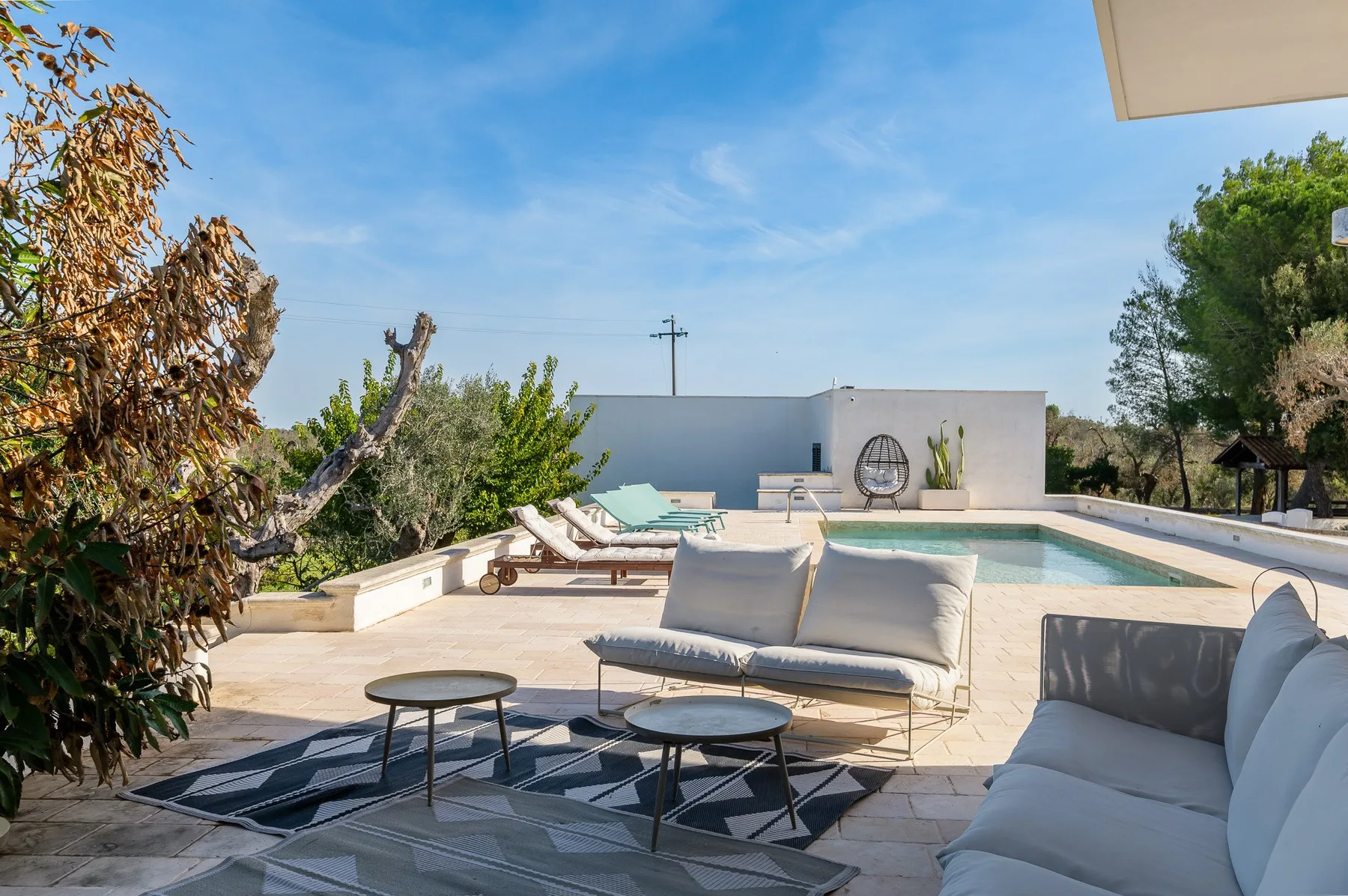 A sunny outdoor terrace features a swimming pool and cushioned seating.