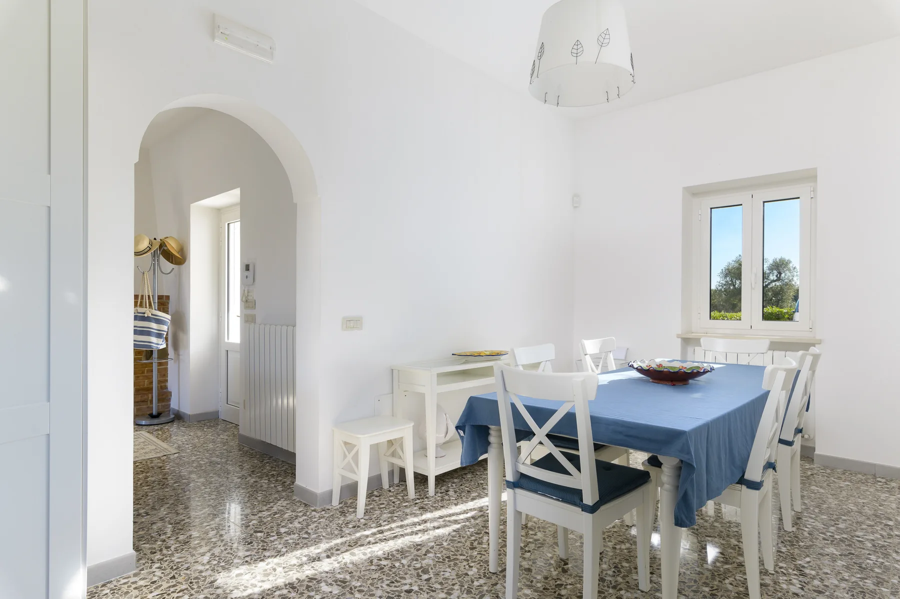 A bright dining room with a blue-covered table and a window.
