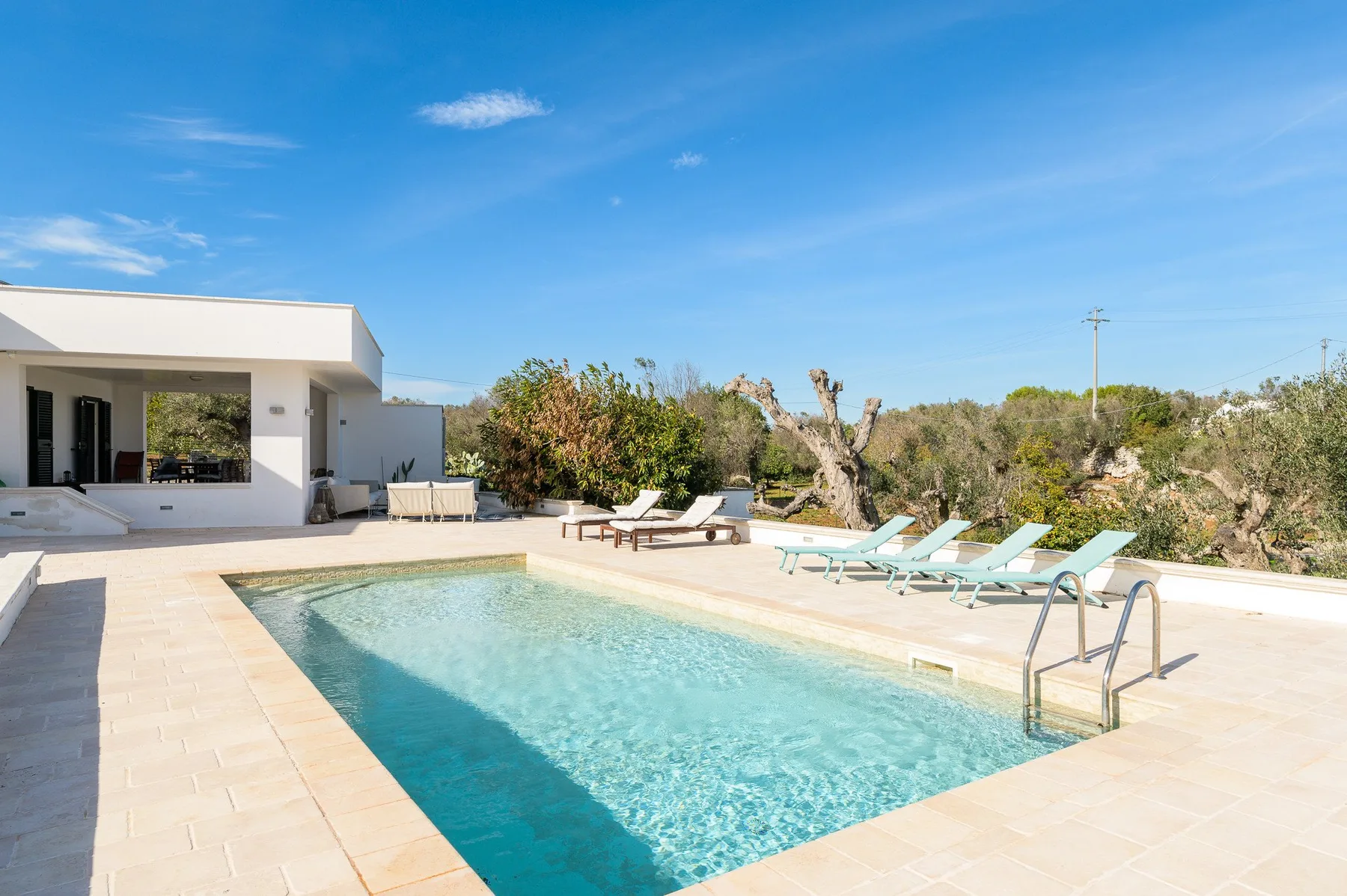 A swimming pool beside a modern house, with lounge chairs along the deck.