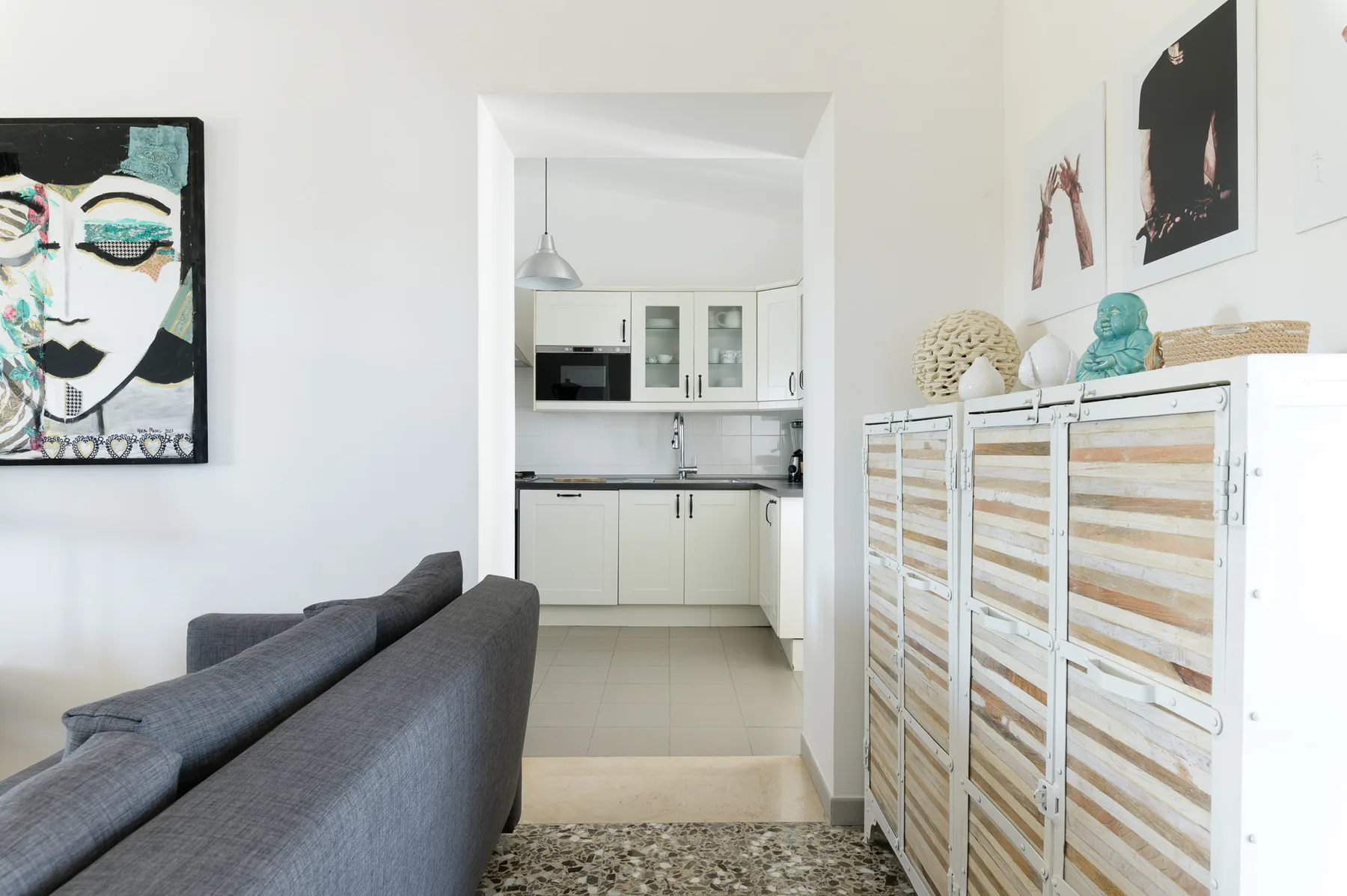 A bright living area opens onto a compact kitchen, with framed artwork on the walls.
