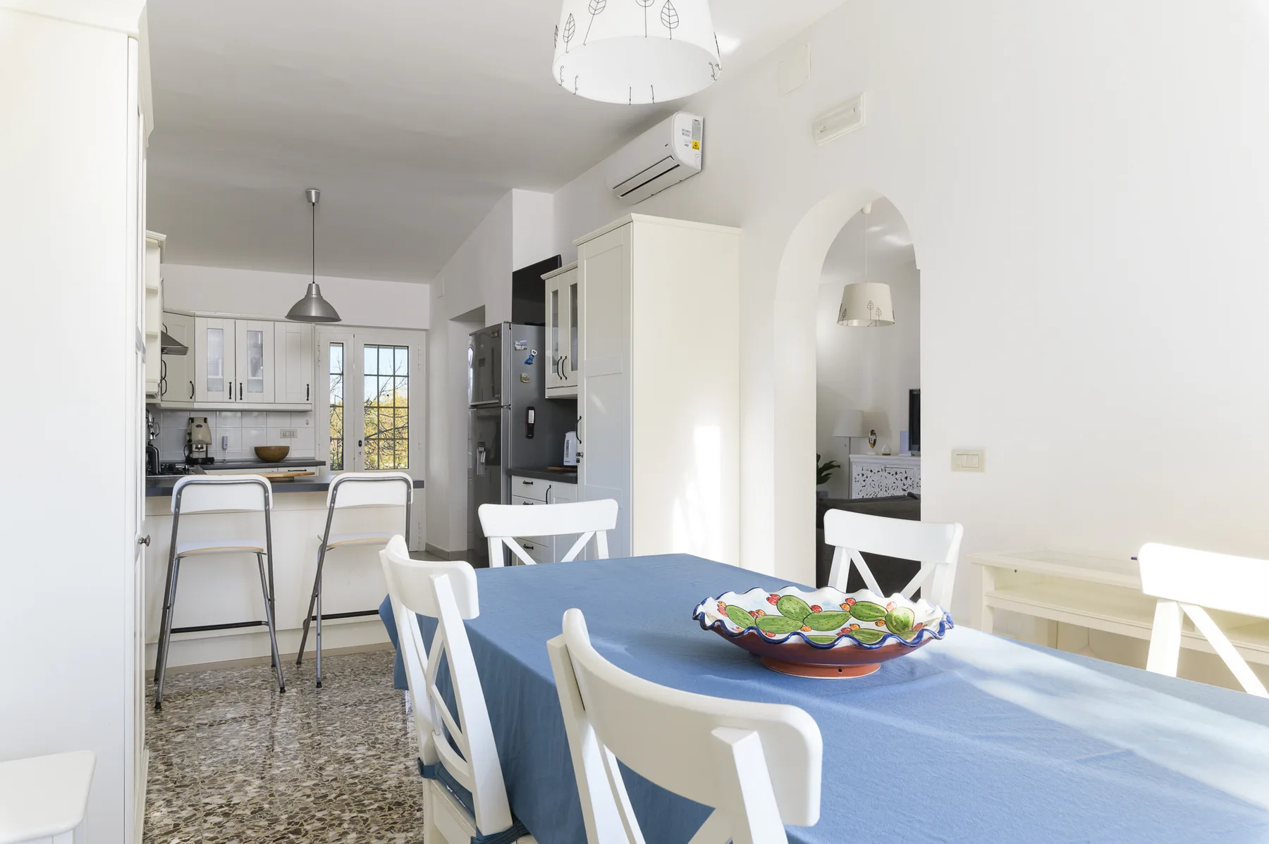 A dining table with white seating sits beside an open kitchen.