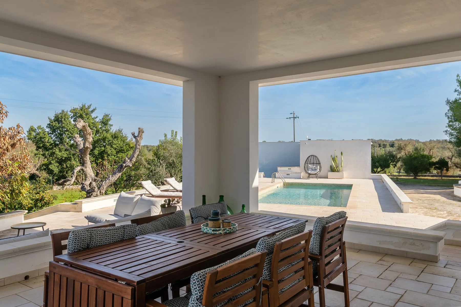 A covered outdoor dining area overlooks a swimming pool and landscaped grounds.