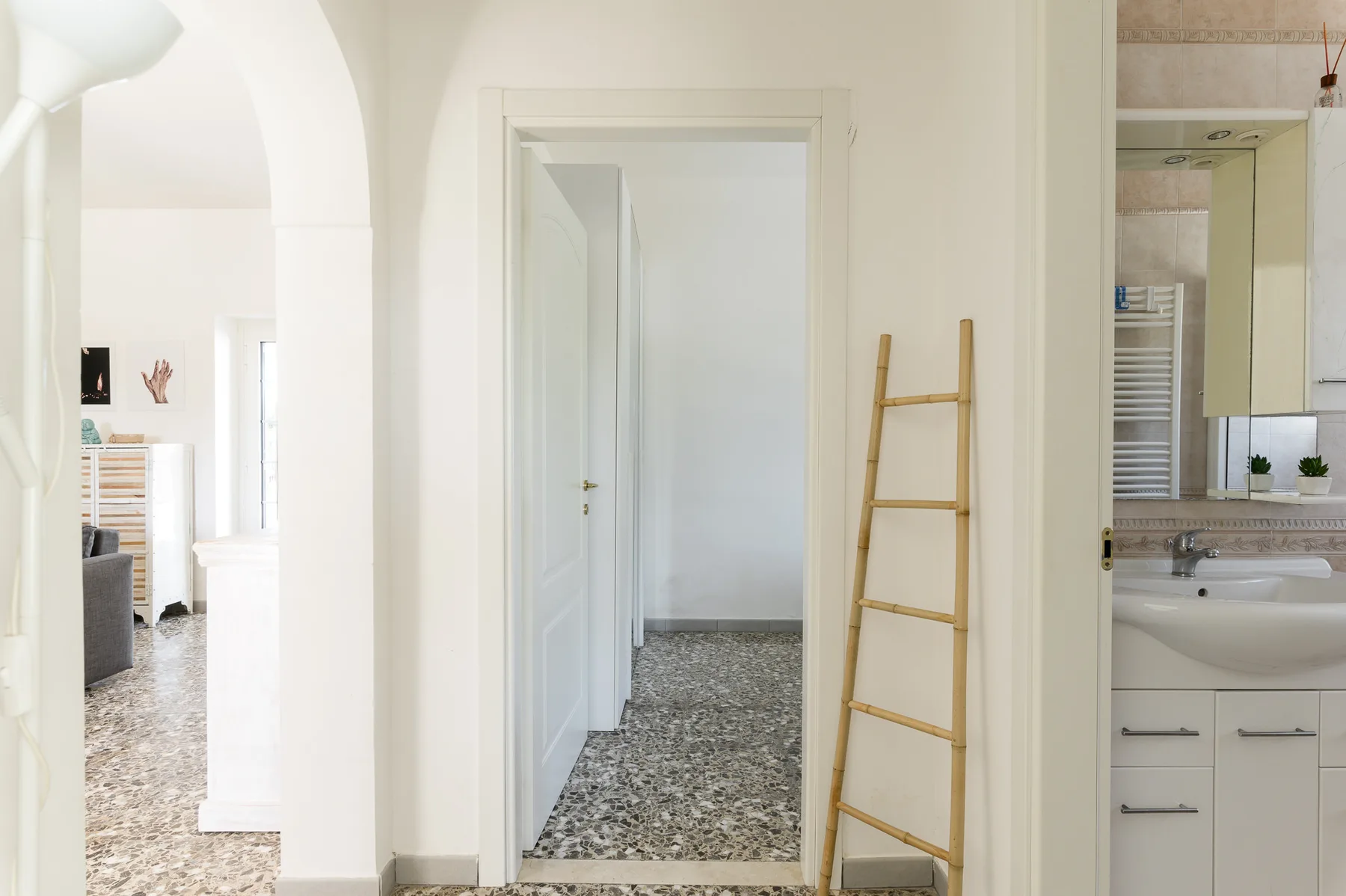 A bright interior hallway with a wooden ladder leaning against the wall.