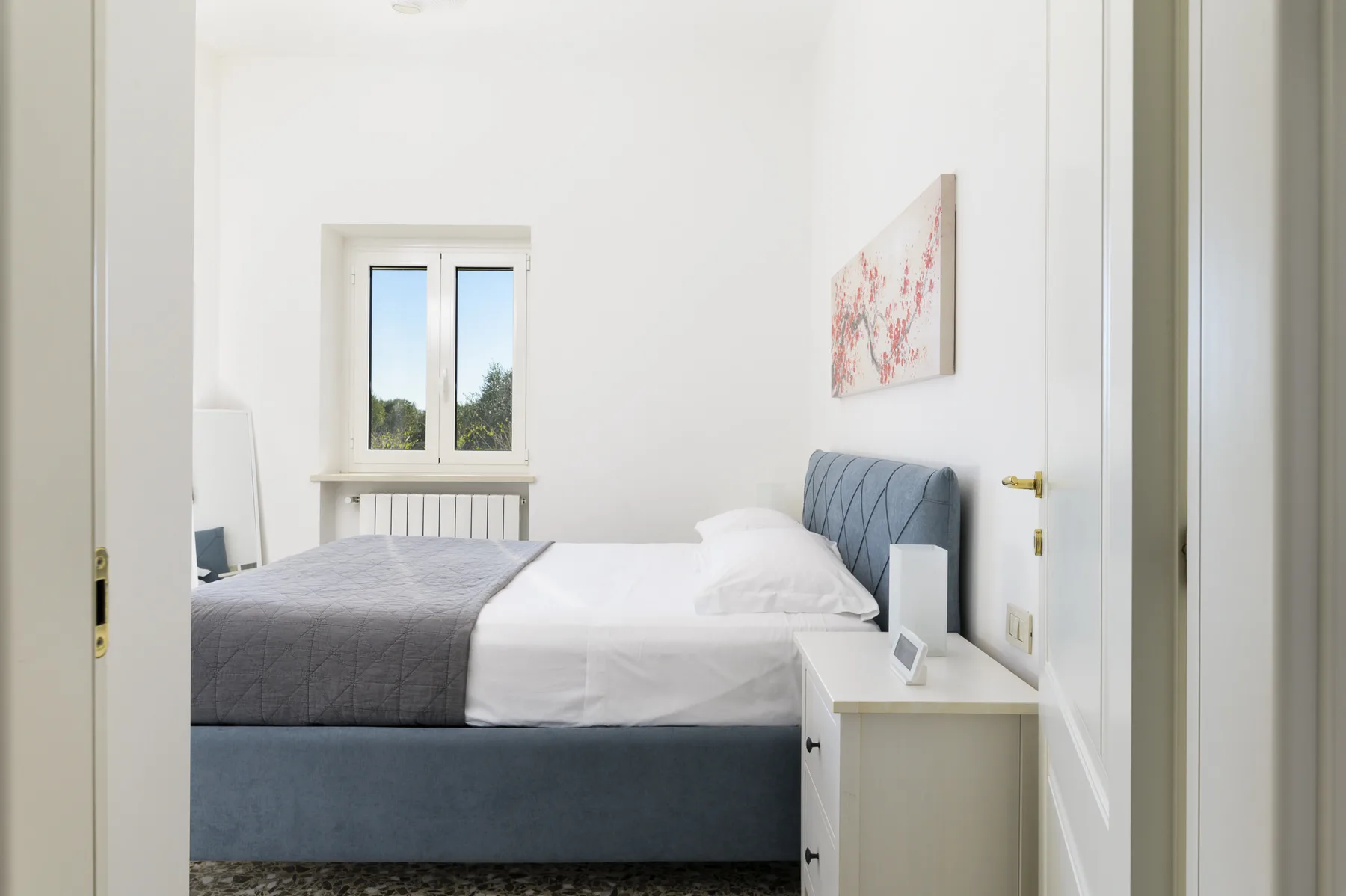 A bright bedroom with a neatly made bed and a window.