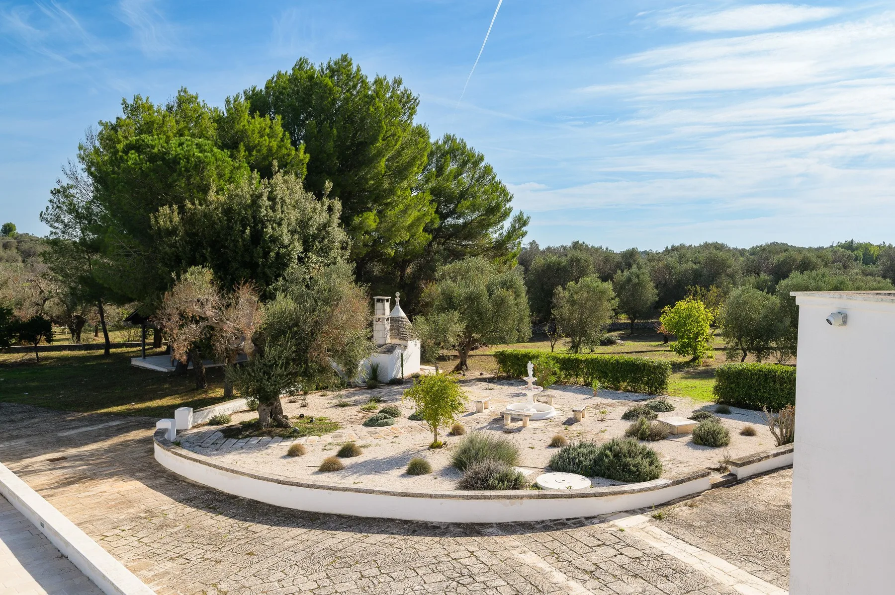 A landscaped garden with a circular stone path and trees under a clear sky.