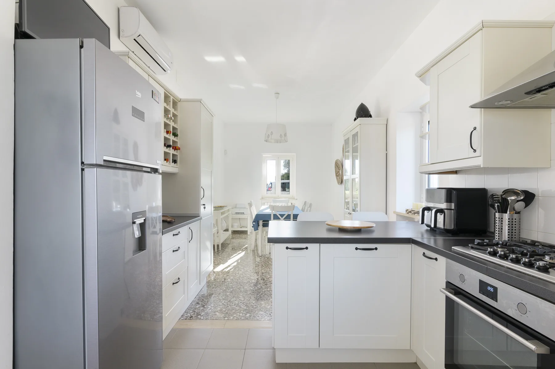 A bright kitchen with white cabinetry, dark countertops, and a central island.