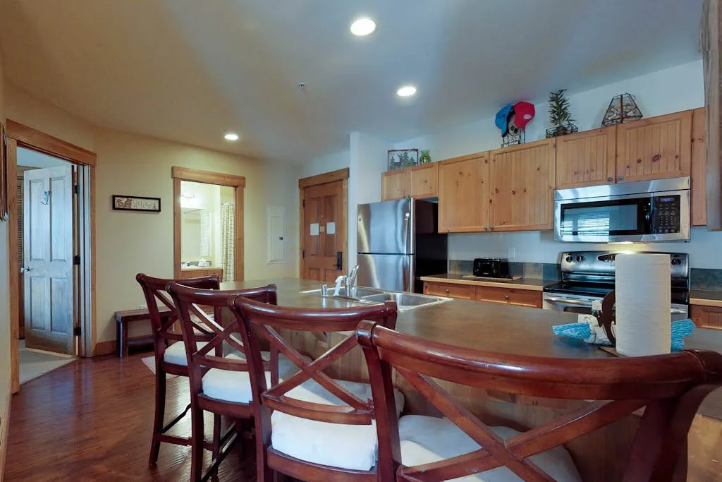 A kitchen and dining area with a wooden table and open kitchen.