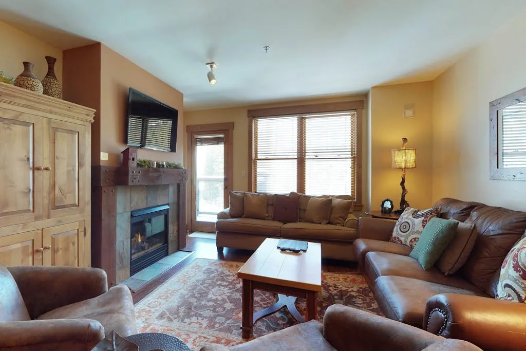 A living room with brown seating, a fireplace, and a coffee table.