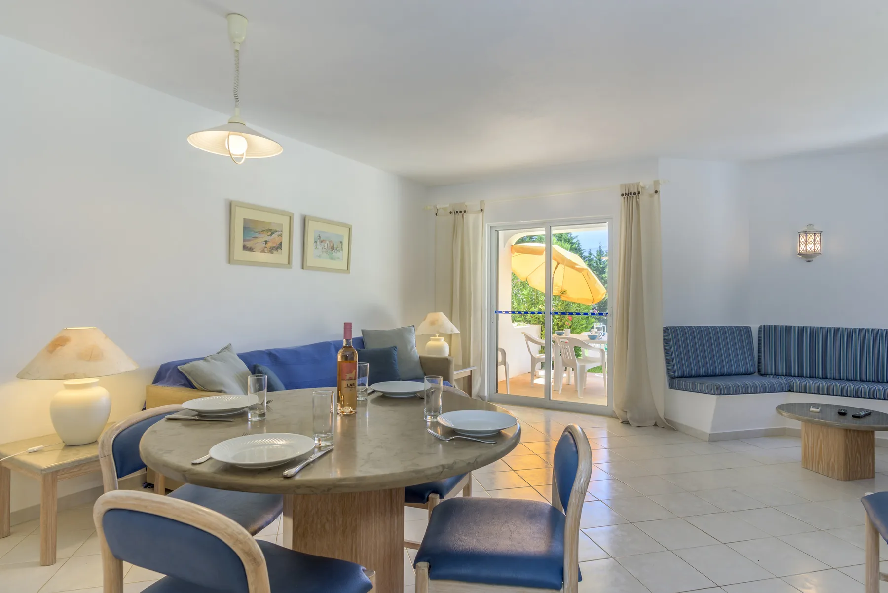 A bright living and dining area with blue seating and a round dining table.
