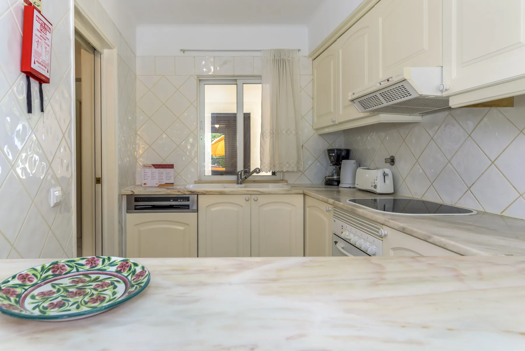 A bright kitchen with cream cabinets and a countertop in the foreground.
