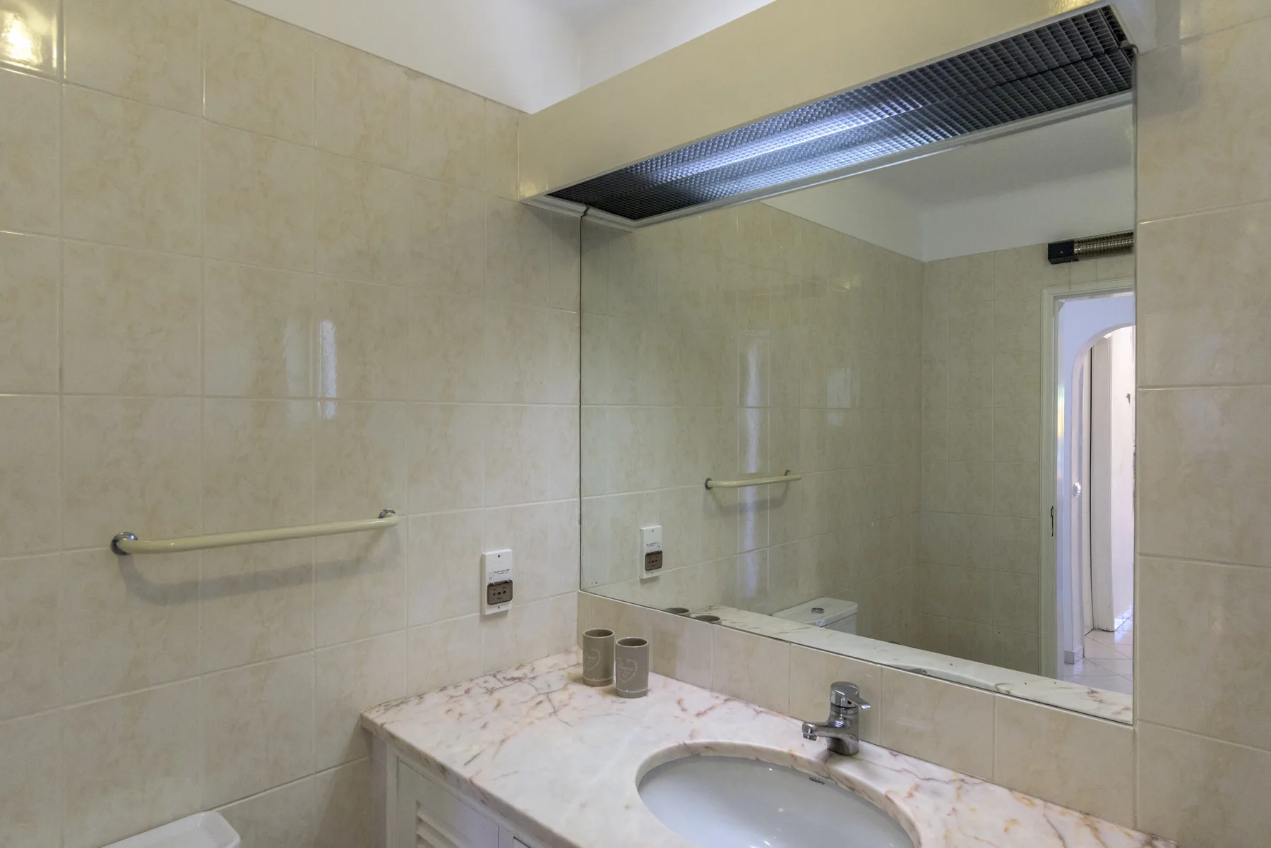 Un baño alicatado con un espejo amplio sobre el lavabo.