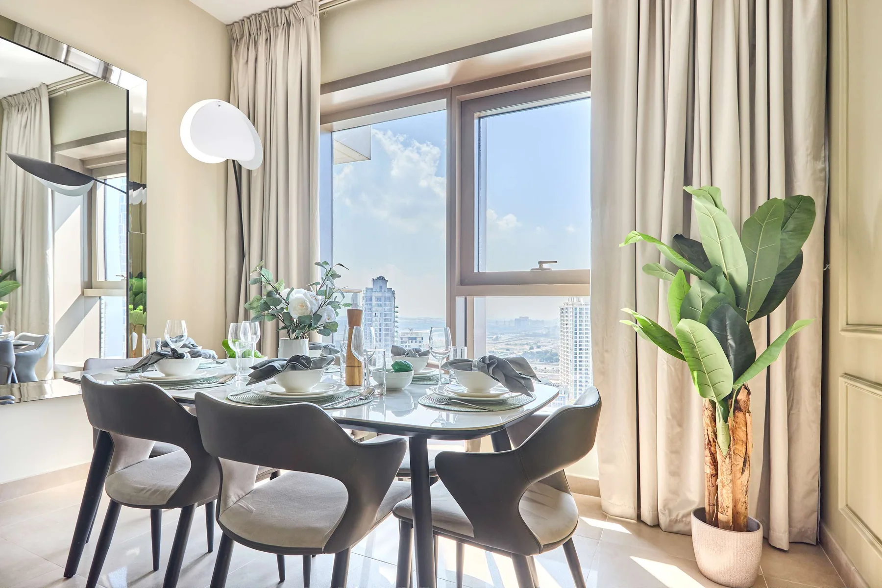 Comedor con la mesa puesta junto a una ventana grande con vistas a la ciudad.