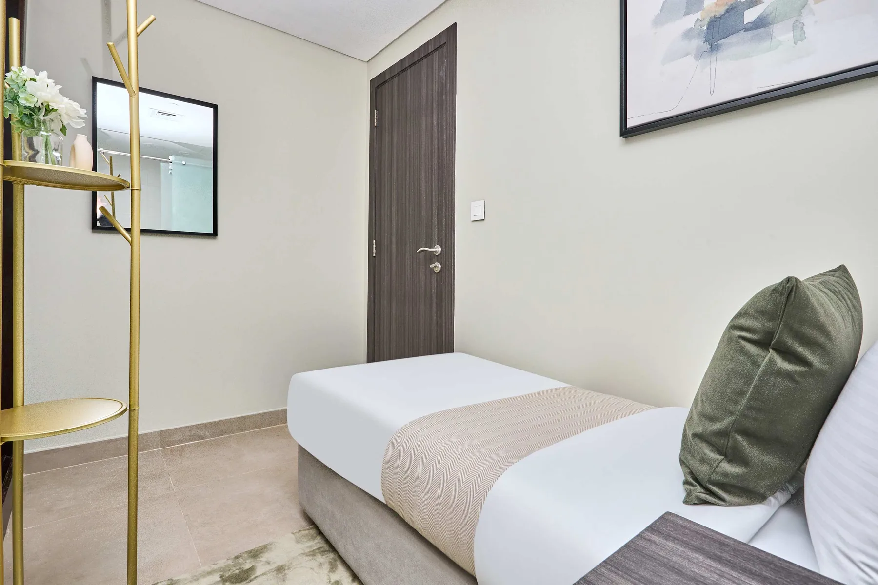 Un dormitorio con una cama bien tendida y una obra enmarcada en la pared.