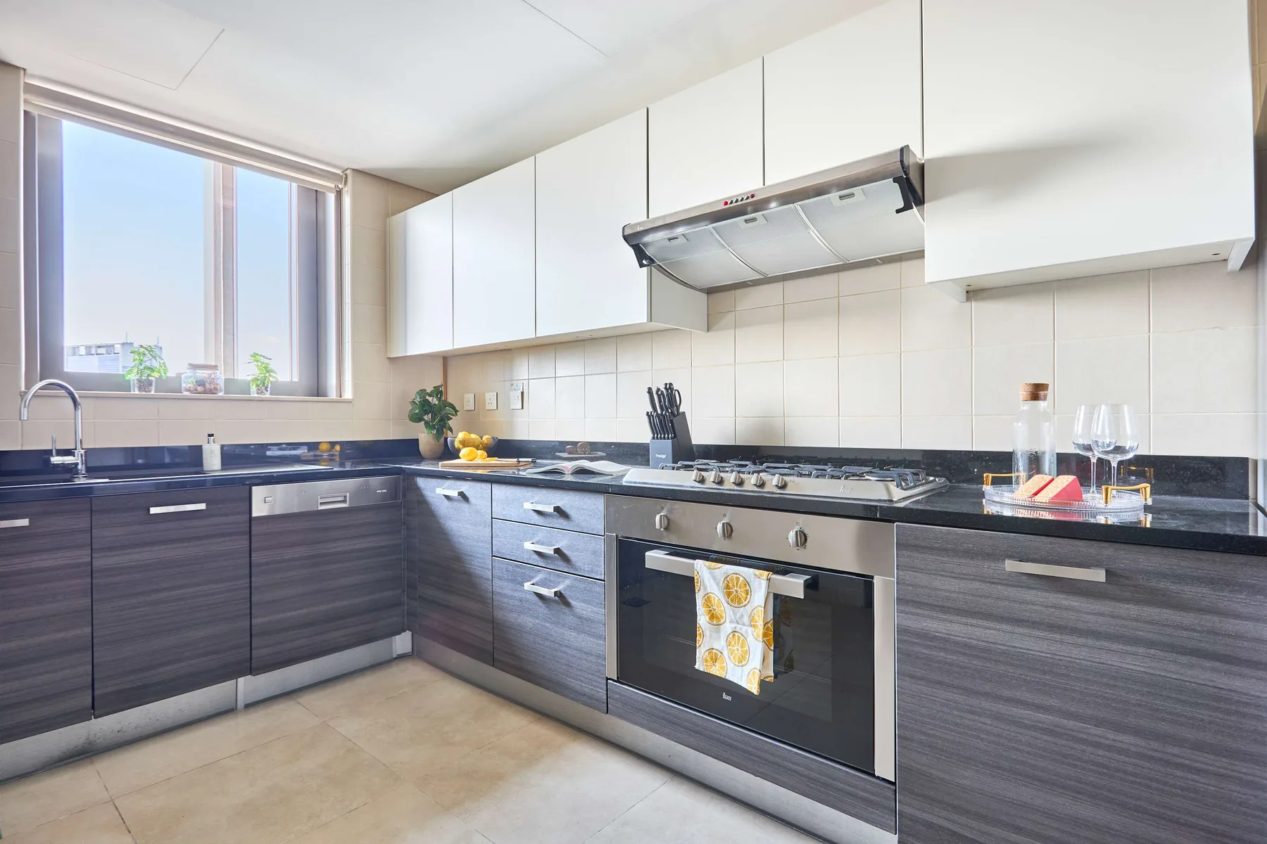 Una cocina luminosa con gabinetes oscuros, encimera y horno integrado.