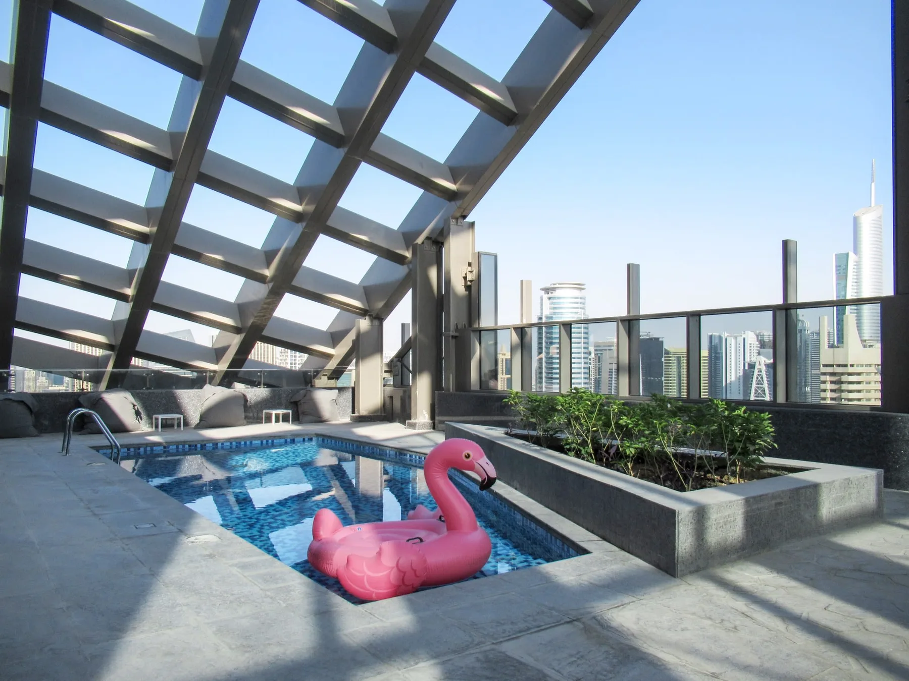 Una piscina en la azotea está bajo una cubierta de vidrio, con edificios al fondo.