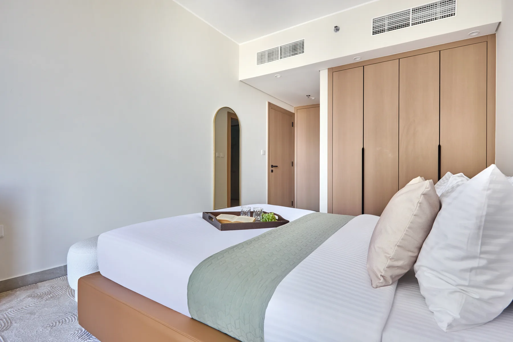 Un dormitorio luminoso con una cama bien tendida y armarios empotrados de madera.