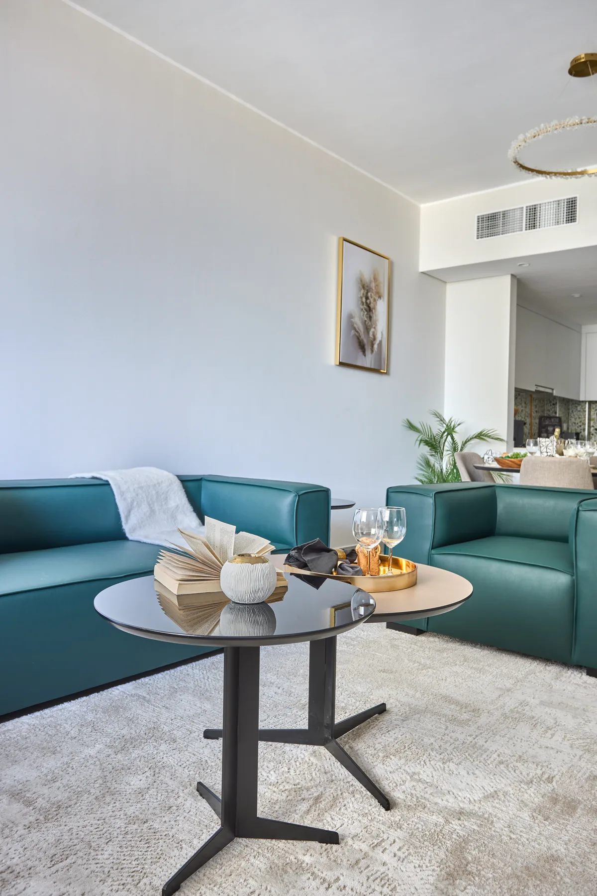 Una sala luminosa con asientos color verde azulado y una mesa de centro redonda.