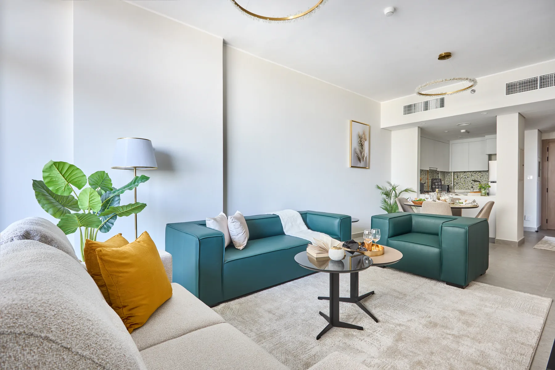 Una sala de estar luminosa con asientos color turquesa y una mesa de centro redonda.