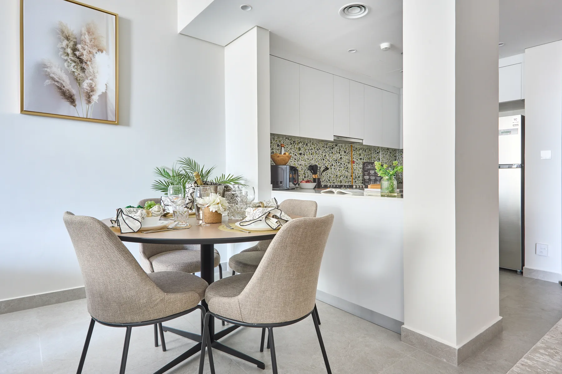 Comedor con la mesa puesta junto a una cocina abierta.
