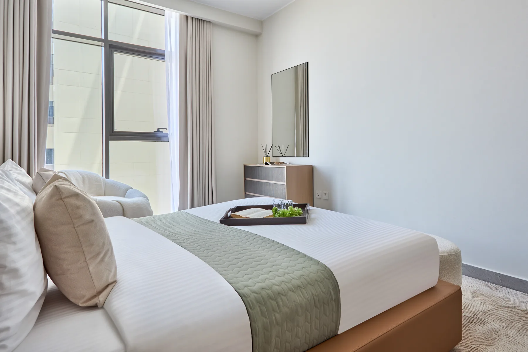 Un dormitorio con una cama bien hecha y una ventana grande.