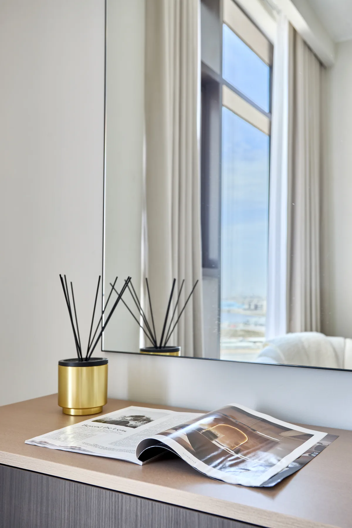 Una zona de estar luminosa con una revista abierta junto a una ventana alta.