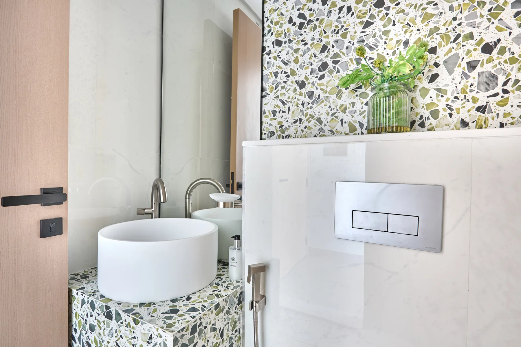 Un baño moderno con un lavabo redondo sobre encimera y superficies de azulejos estampados.