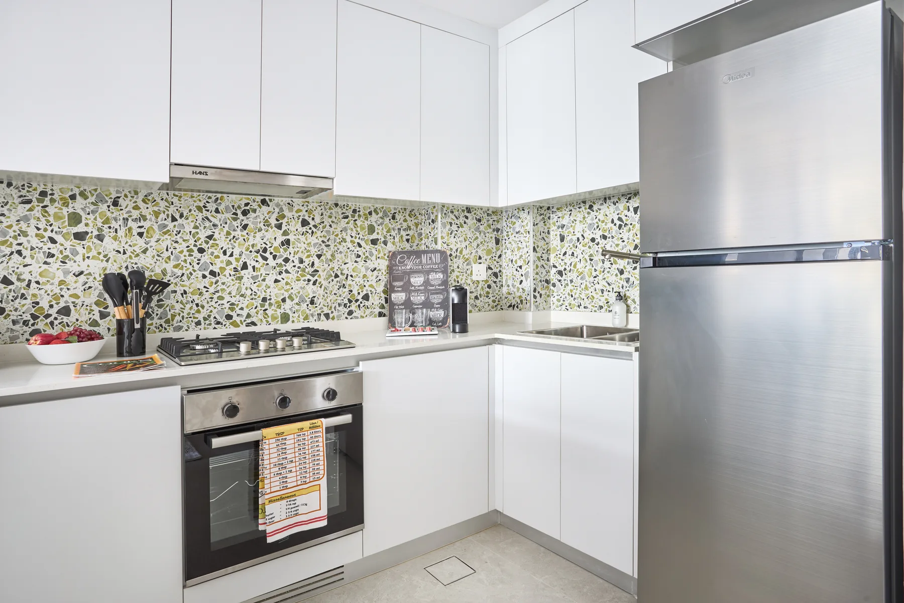 Una cocina moderna y luminosa con gabinetes blancos y electrodomésticos de acero inoxidable.