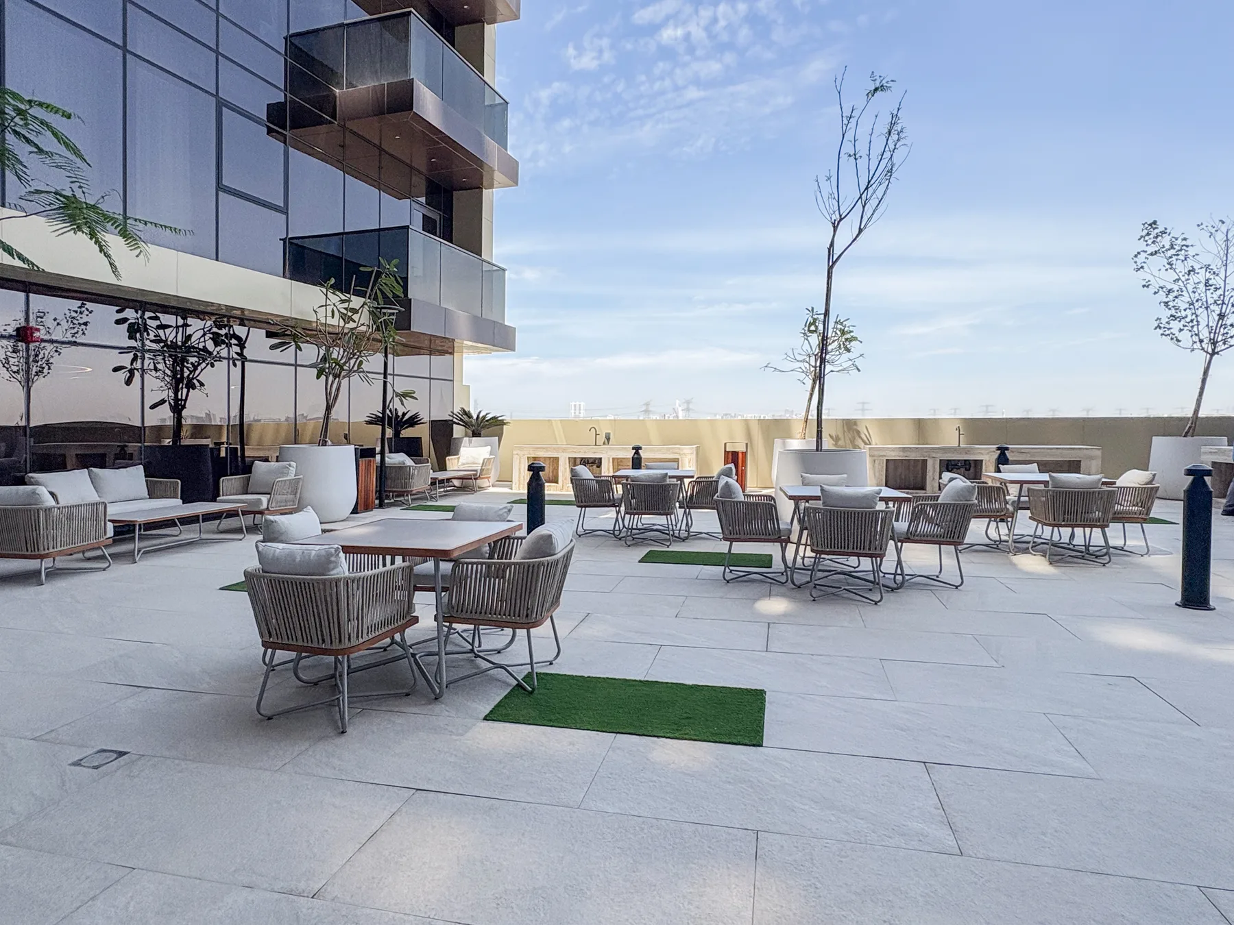 Una terraza al aire libre con asientos alrededor de mesas junto a un edificio moderno.