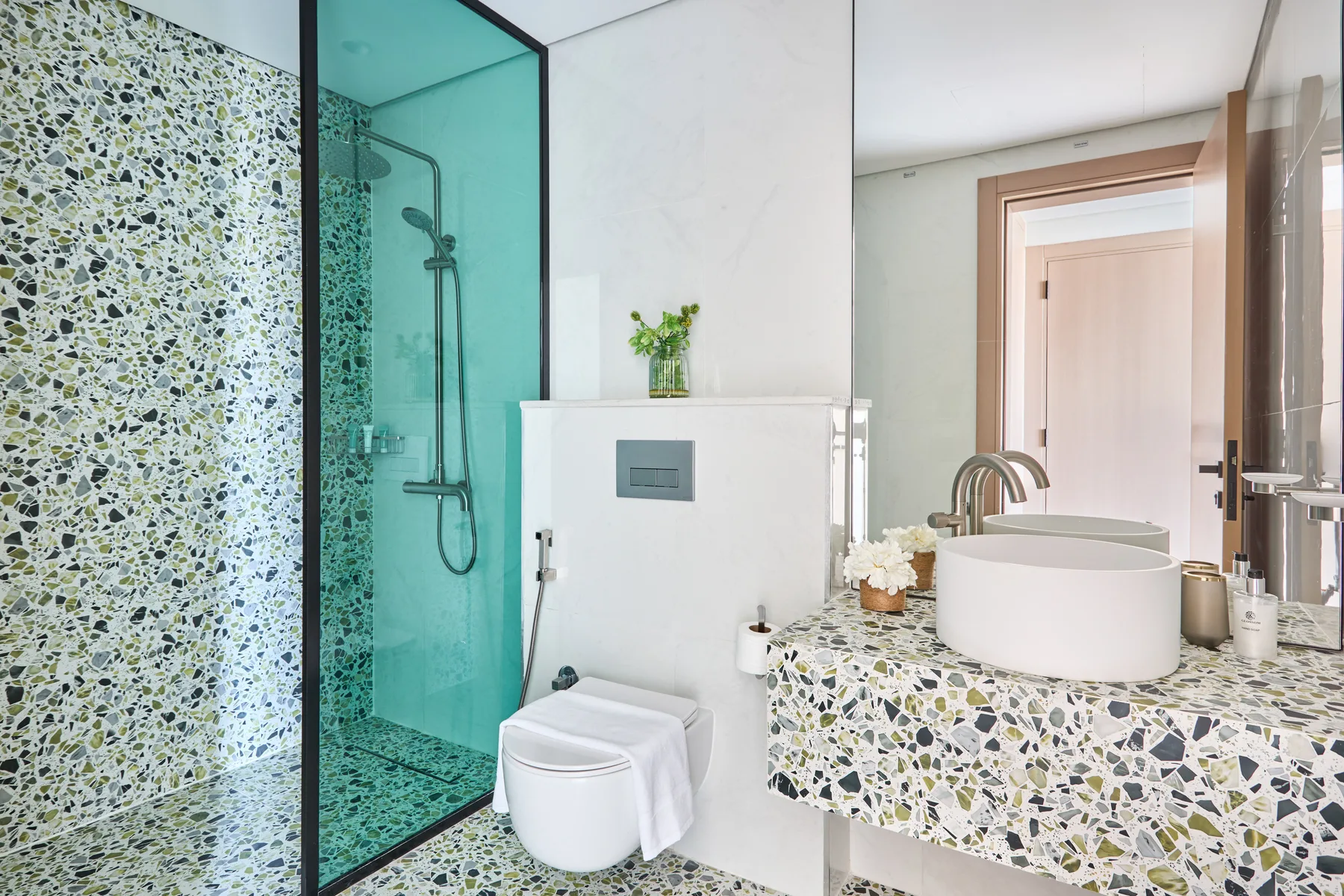 Un baño con un lavabo de mosaico y una ducha con mampara de vidrio.