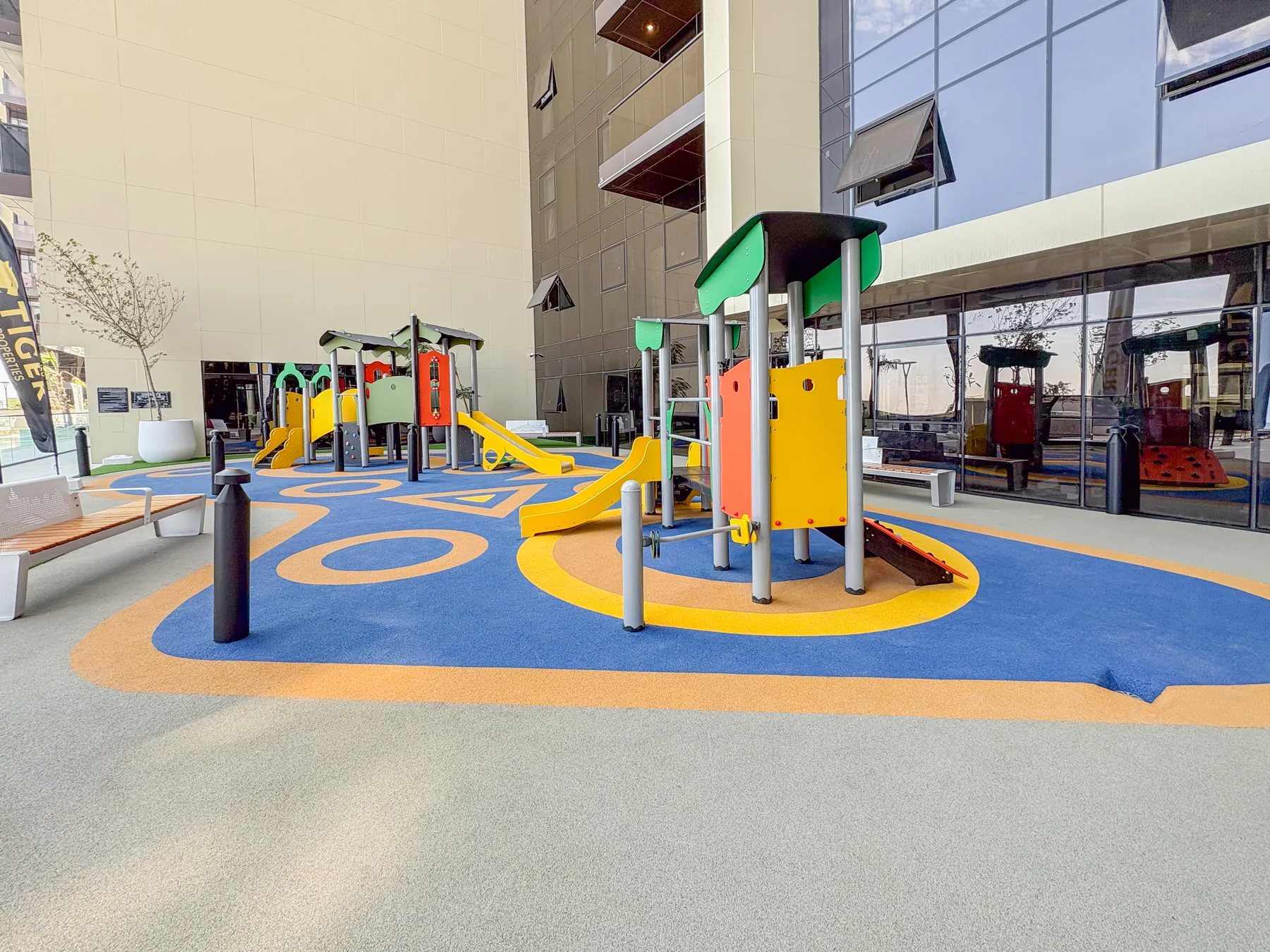 Un parque infantil interior con juegos coloridos sobre un suelo estampado.