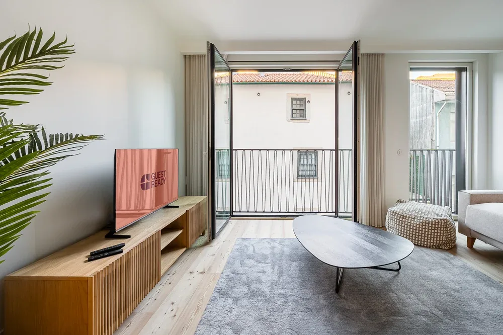 A bright living room opens onto a balcony, with a television and low table.