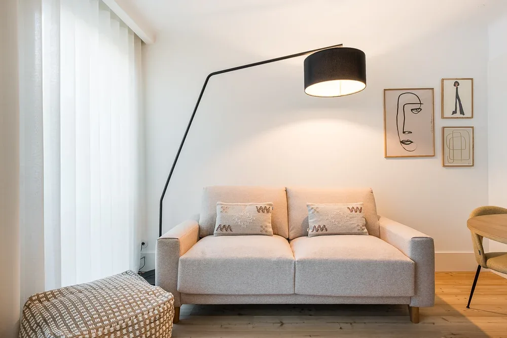 A bright living room with a gray sofa and a tall arched floor lamp.