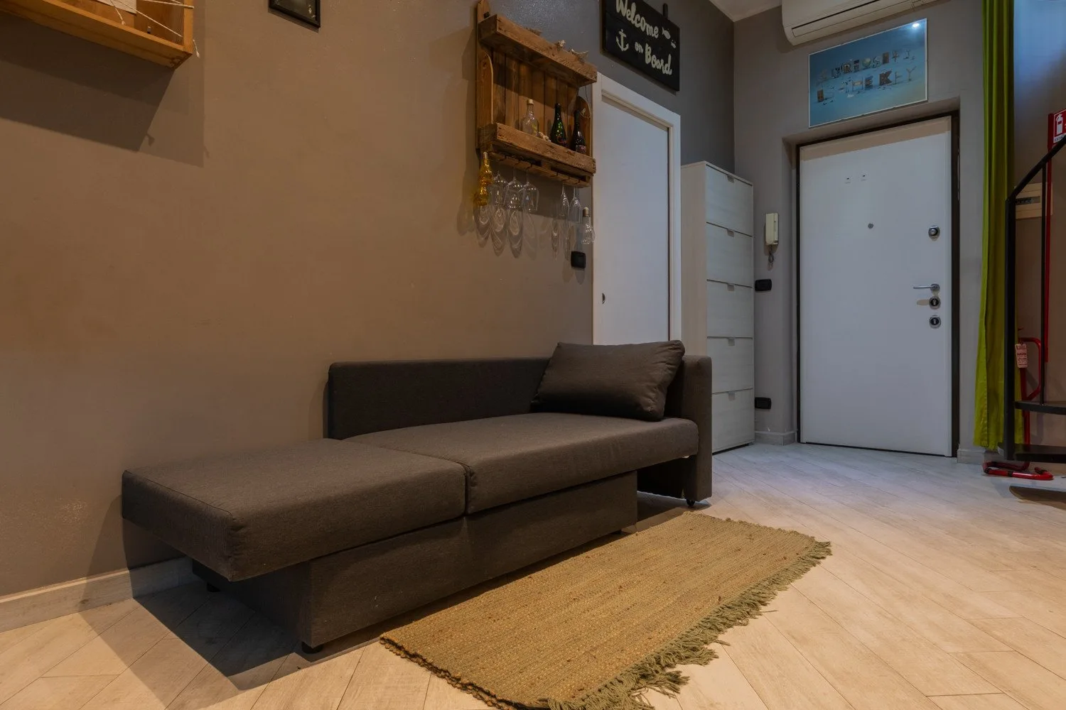 An entryway seating area with a long upholstered bench and a woven rug.