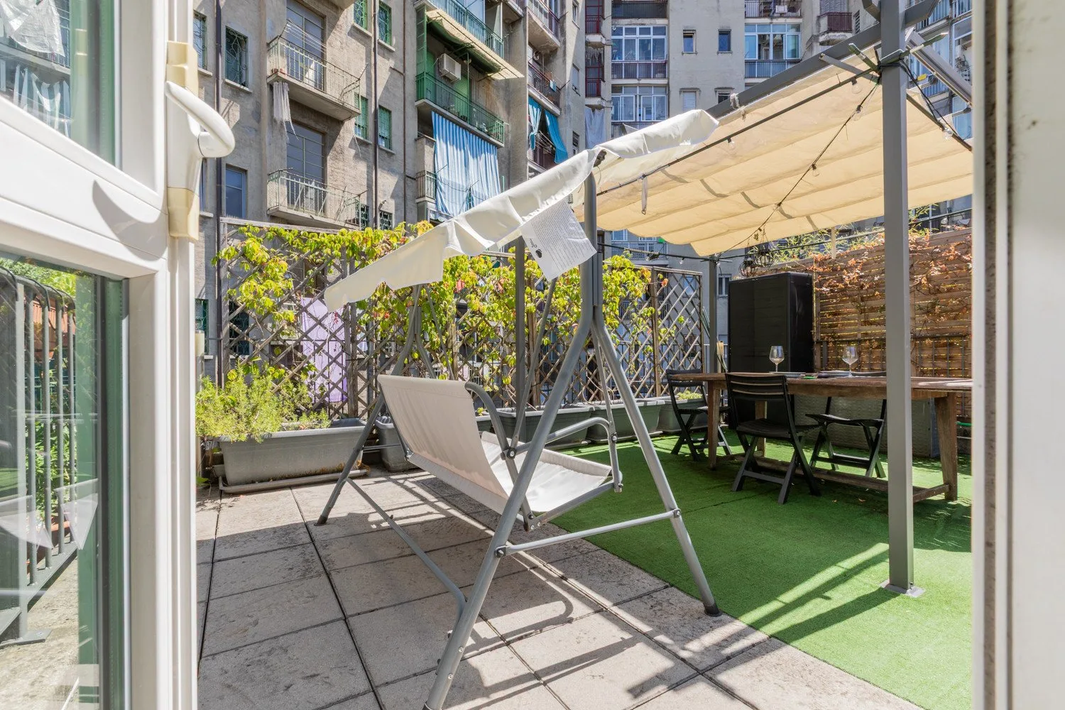 A rooftop terrace with a shaded seating area and a swing.