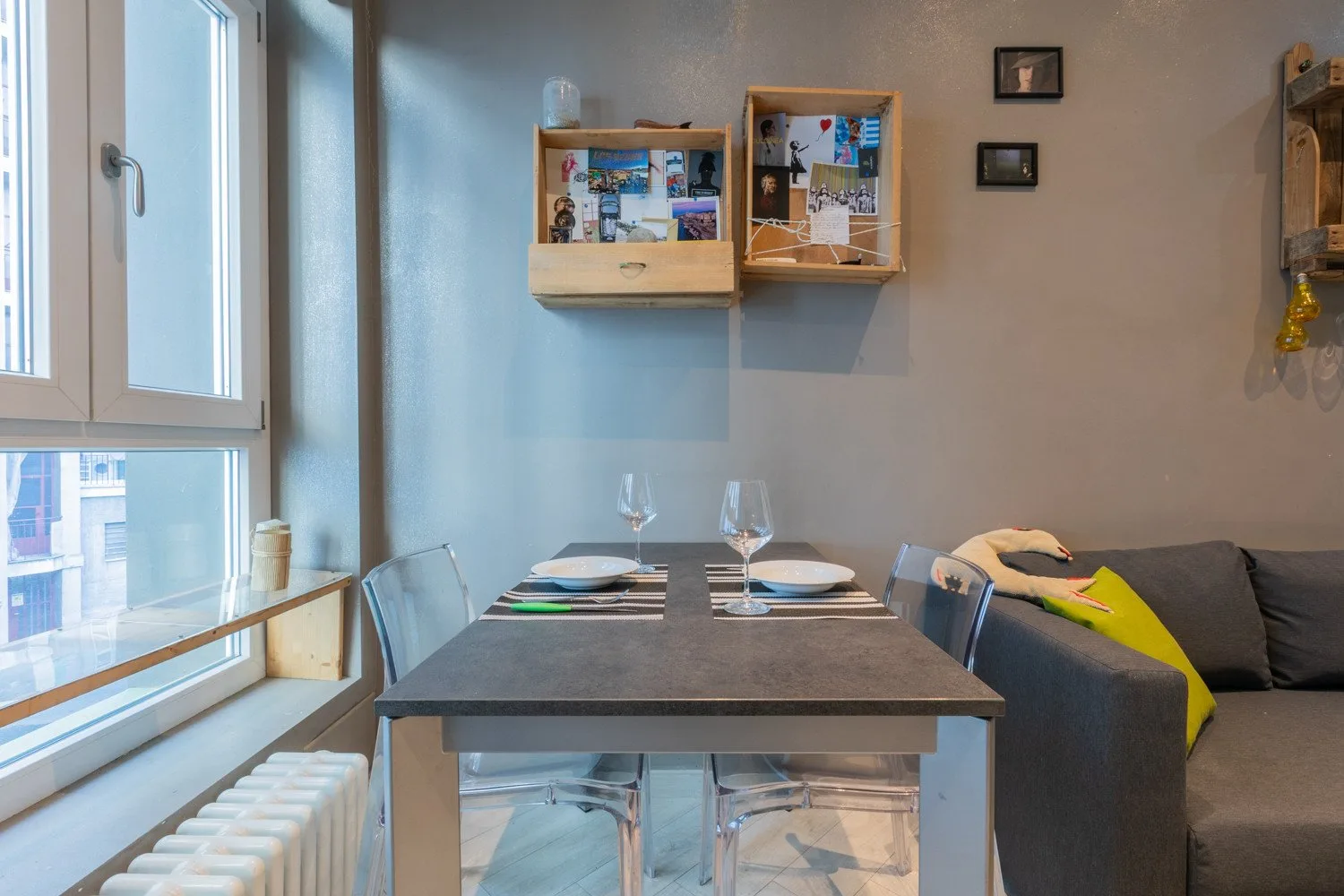A dining table sits beside large windows in a compact living and dining area.