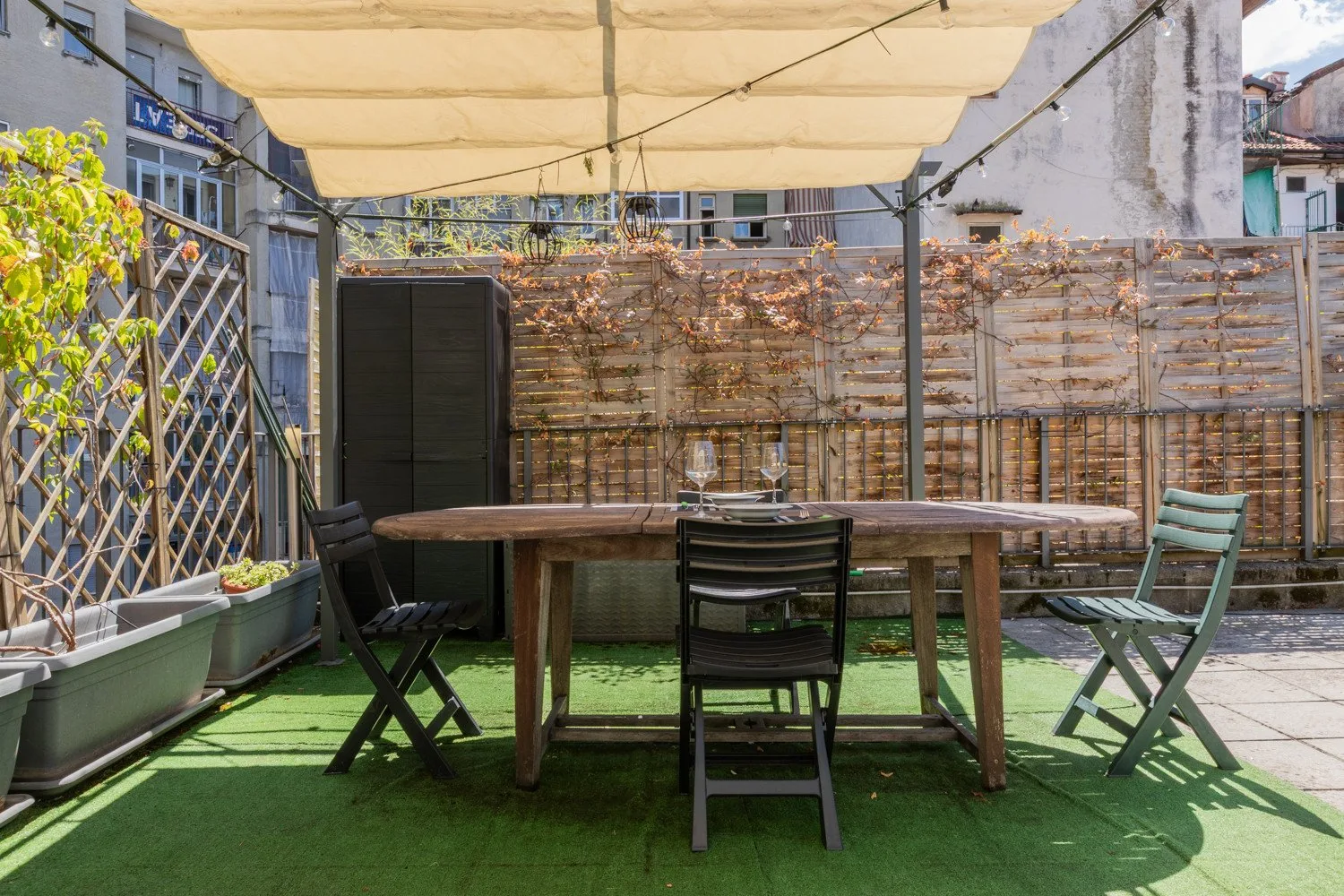 An outdoor dining area with a long table and chairs beneath a canopy.