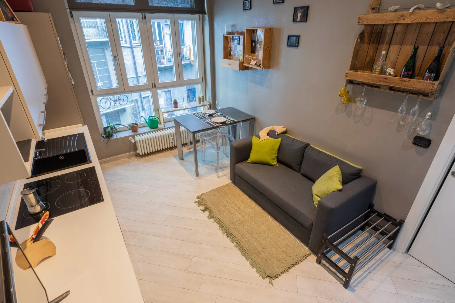 A compact living area with a sofa, dining table, and large windows.