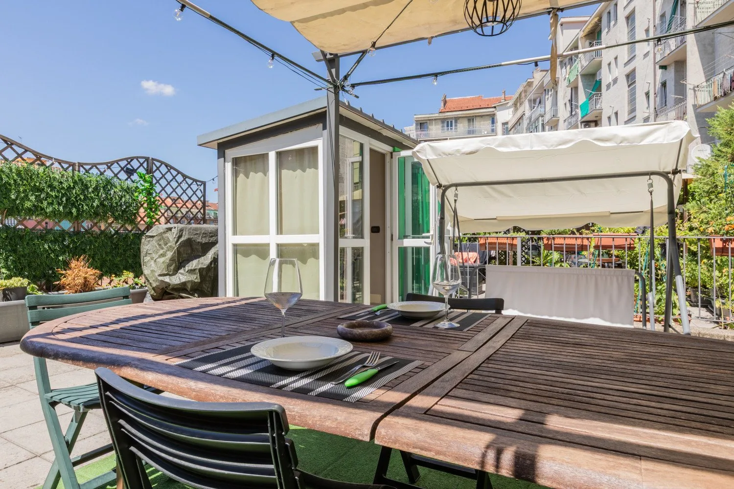 An outdoor dining area with a long table set beneath a canopy.